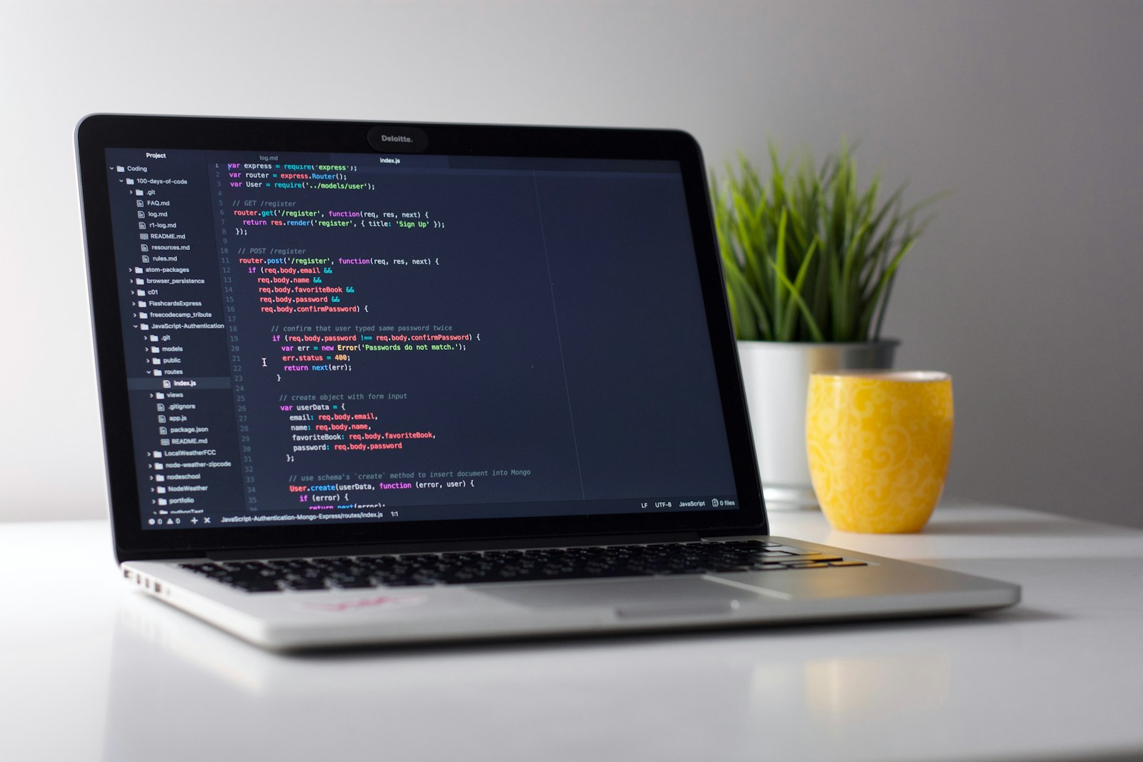 A MacBook on a clean desk showing a code editor with project files in the sidebar and a small plant beside the keyboard โ the daily-driver setup for iOS development with AI tools