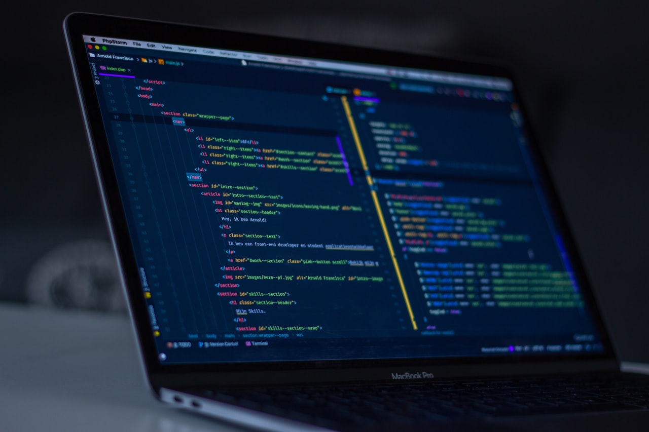 A developer at a workstation with multiple monitors showing game engine code and 3D asset work โ the kind of specialized environment that took years to build expertise in, now disrupted by rapid market contraction