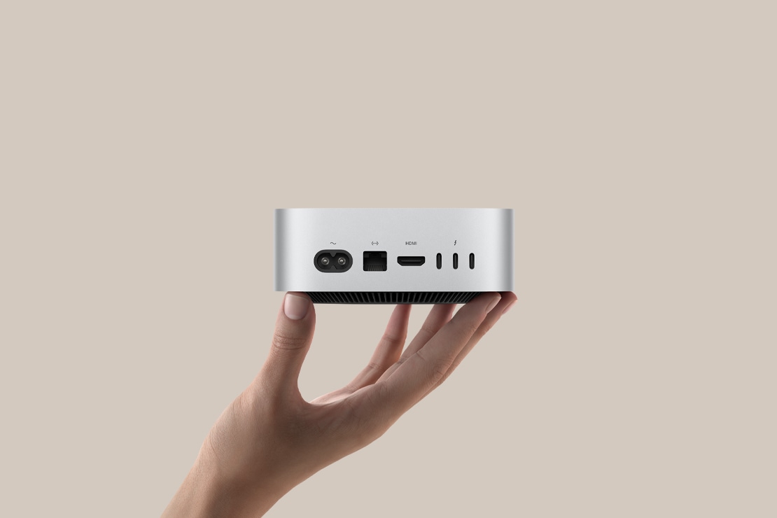 The M4 Mac Mini held in one hand, showcasing its compact aluminum design that Perplexity leverages as the hardware foundation for Personal Computer